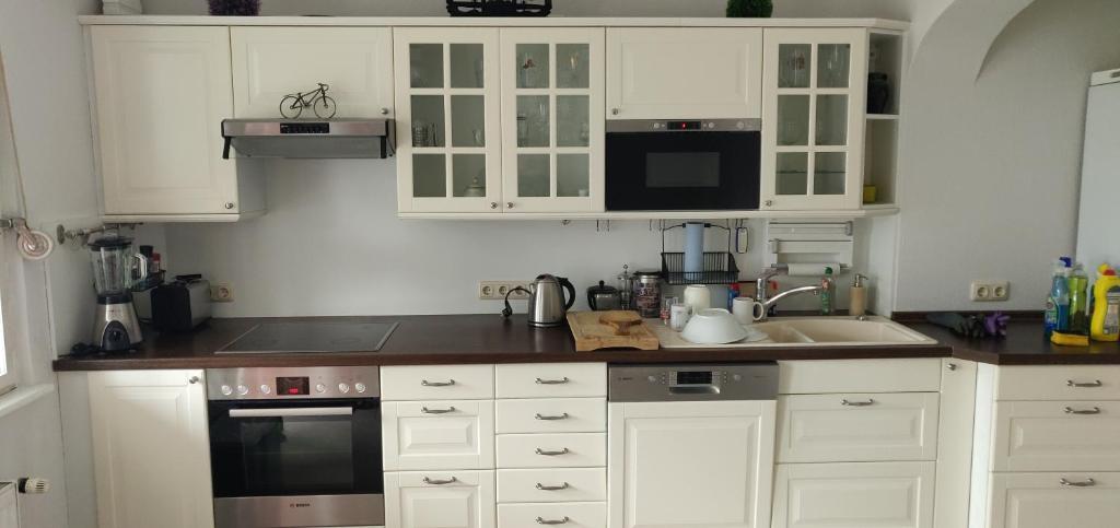 a kitchen with white cabinets and a sink at Ferienhaus Elstal in Wustermark