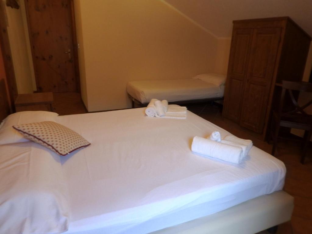 a bedroom with two beds with white sheets and towels at Hotel Sciatori in Sestriere