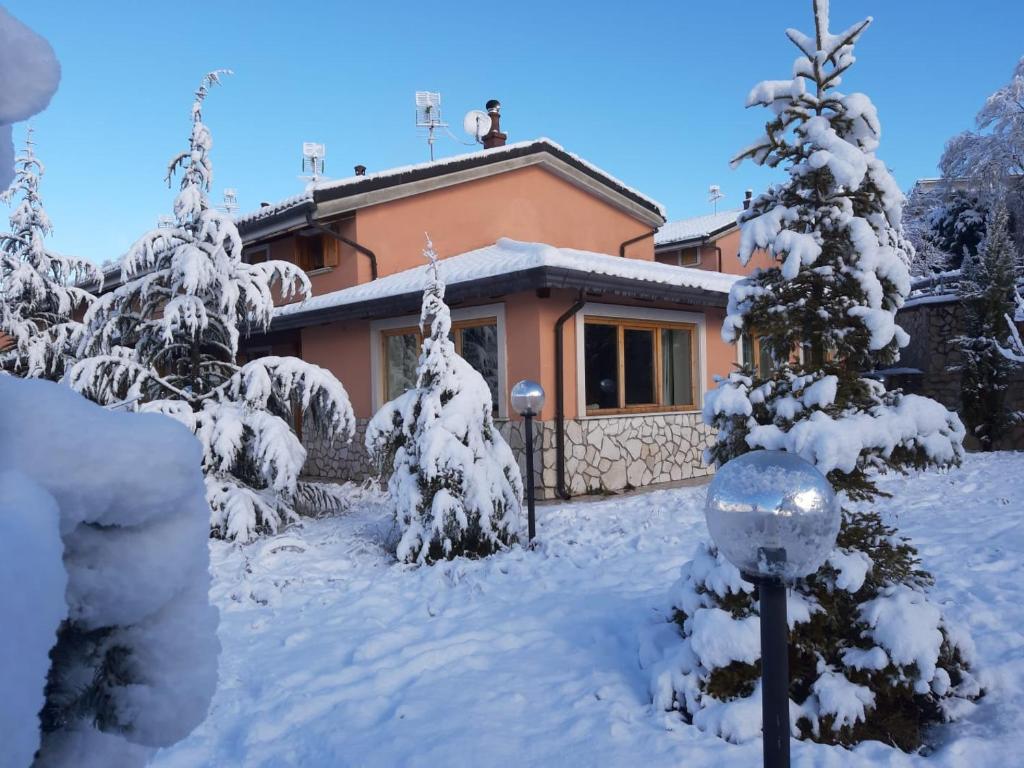 une maison avec des arbres enneigés devant elle dans l'établissement Villa Russo, à Castel di Sangro