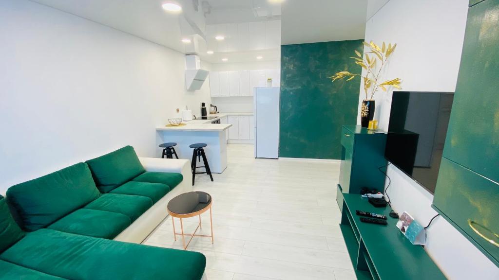 a living room with a green couch and a kitchen at Green & White Apartament in Anykščiai
