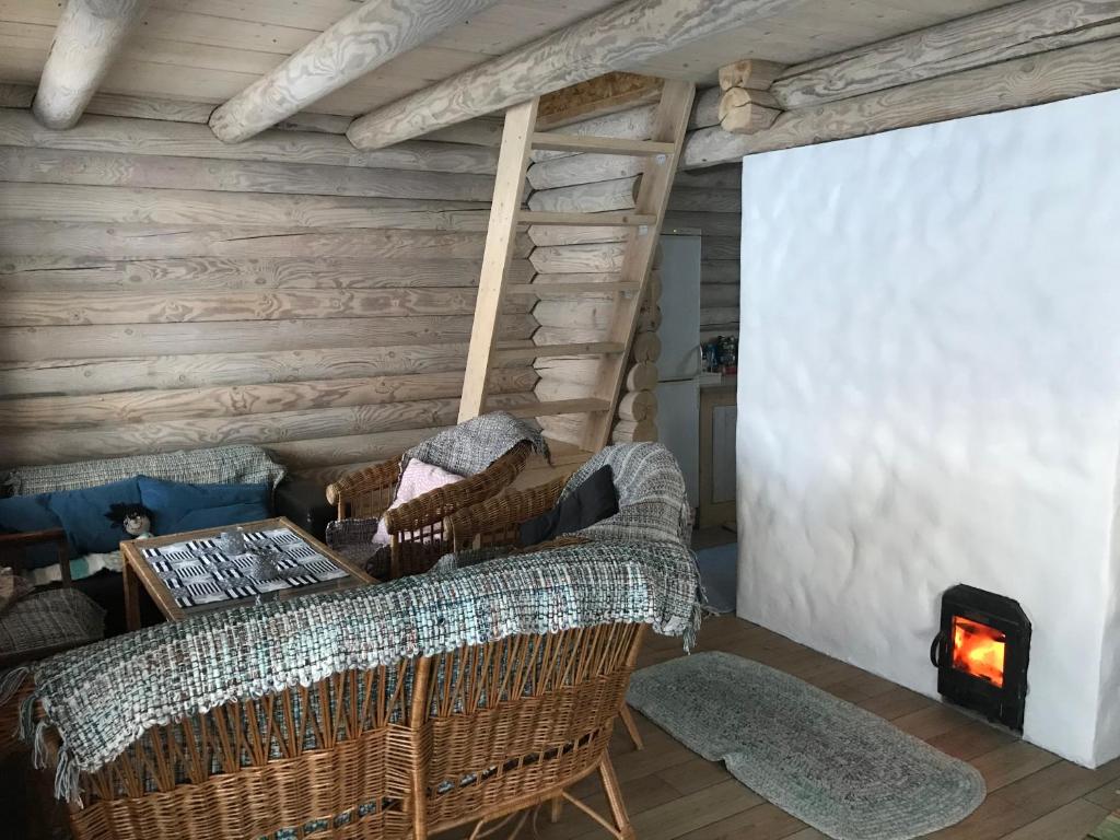 a living room with wicker chairs and a fireplace at Romantic stay at loghouse VäikeTeeMaja in Üksnurme