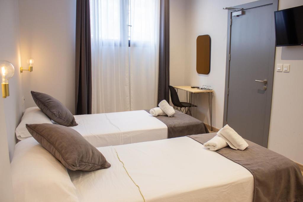 a hotel room with two beds and a television at Pensión B4R in Bilbao