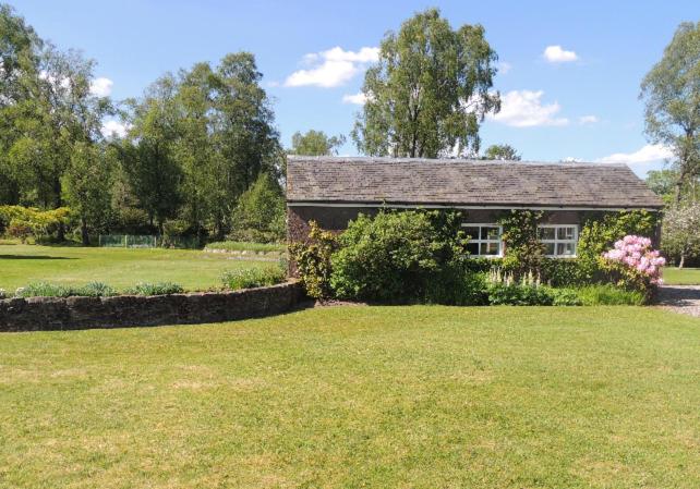 una casa en un campo con un patio de hierba en Woodside Cottage Self Catering, en Kinbuck