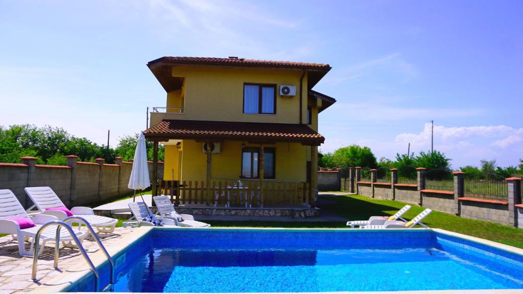 a house with a swimming pool with chairs and a house at Вила Делфин - Villa Delfin in Bŭlgarevo