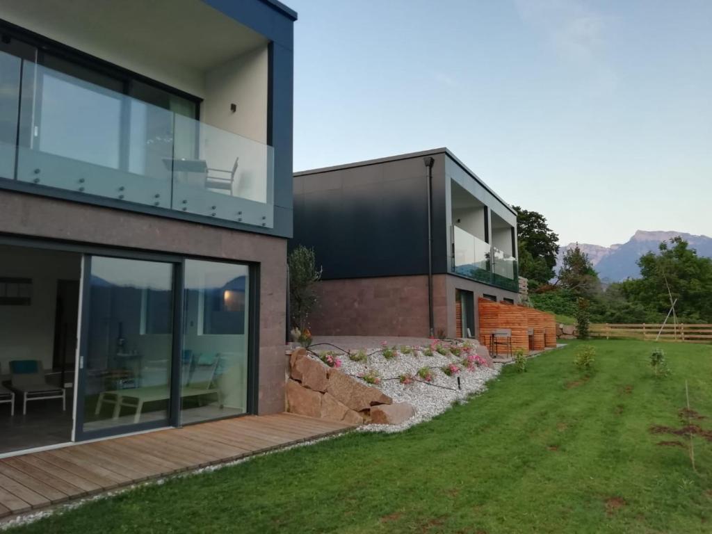 a modern house with glass doors and a yard at AGRITUR SEDICI - Bed and Breakfast in Tenna 