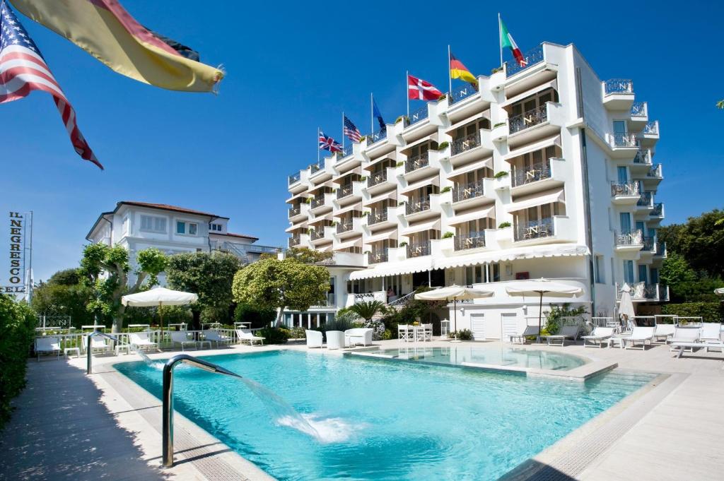 ein Hotel mit einem Pool vor einem Gebäude in der Unterkunft Hotel Il Negresco in Forte dei Marmi