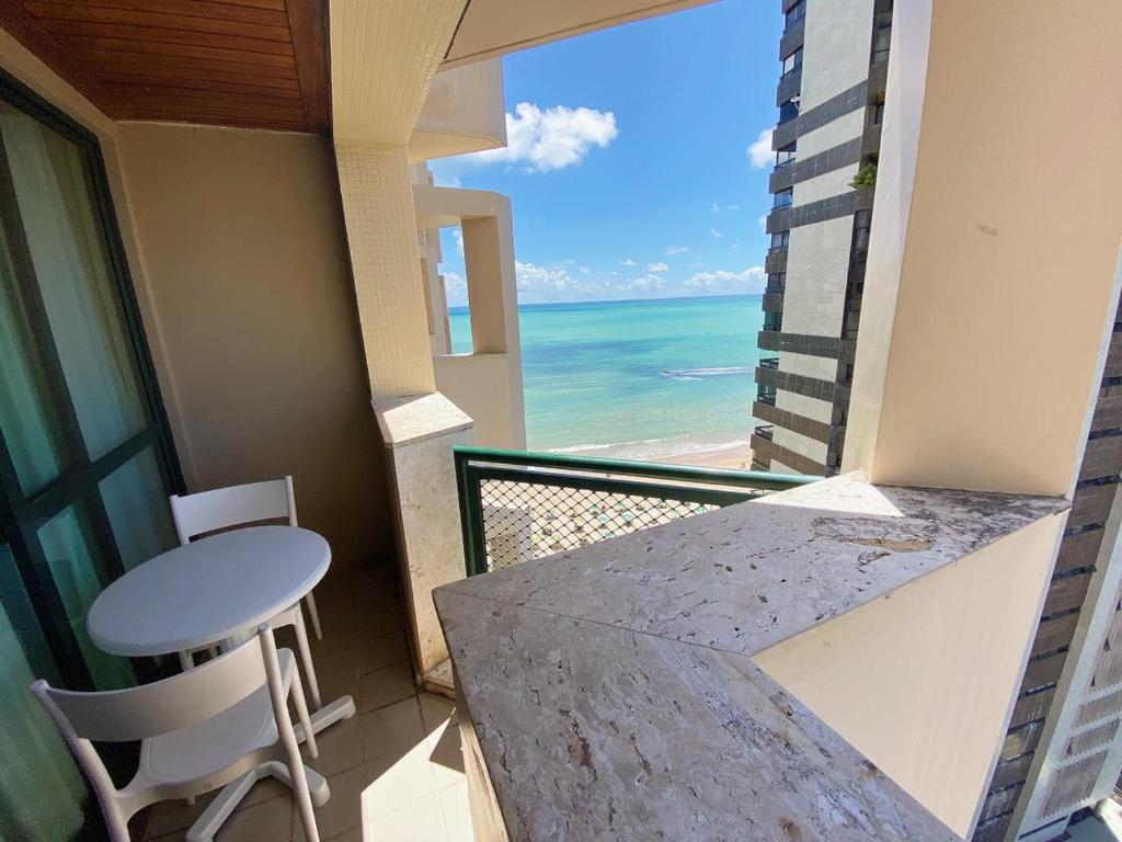 balcón con mesa y vistas al océano en Flat Costa Mar en Recife