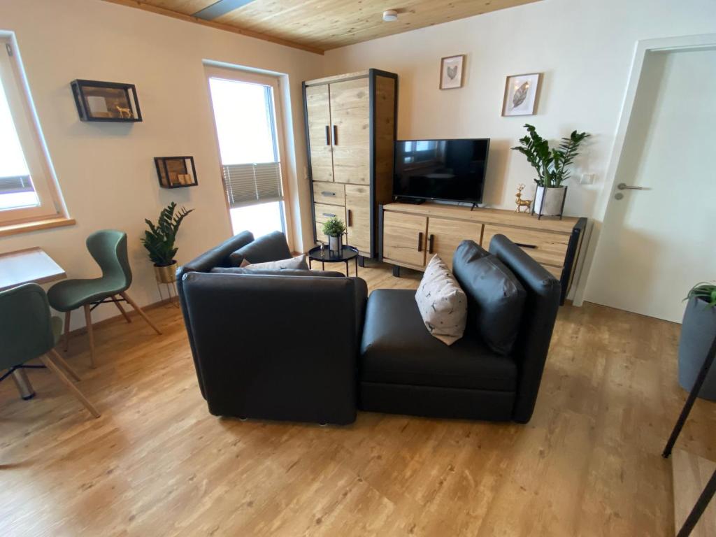 a living room with a black couch and a television at Ferienwohnung mit eigenem Garten und Bergblick in Oy-Mittelberg