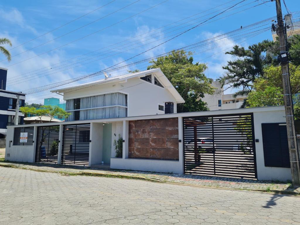 una casa blanca con puertas metálicas de garaje en una calle en Residencial Rumo ao Mar - Bombinhas-SC, en Bombinhas