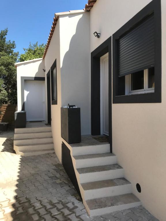 ein weißes Haus mit einer Treppe, die zu einer Tür führt in der Unterkunft Beach House in Fos-sur-Mer