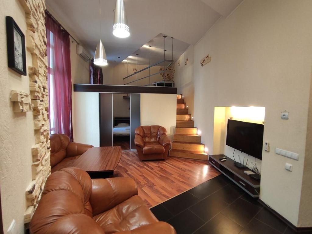 una sala de estar con muebles de cuero y una escalera. en Comfortable Apartment on Mikhaylovskiy lane, en Kiev
