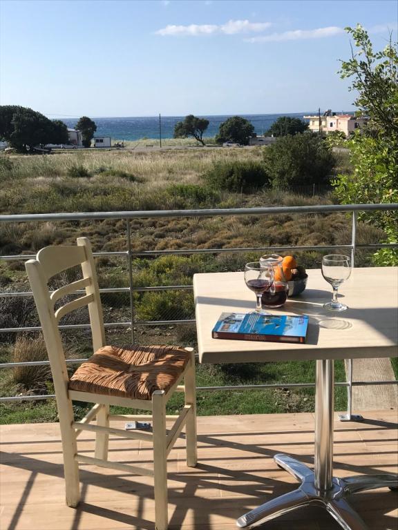 a table and chair on a deck with a view of the ocean at Blue Sky in Frangokastello