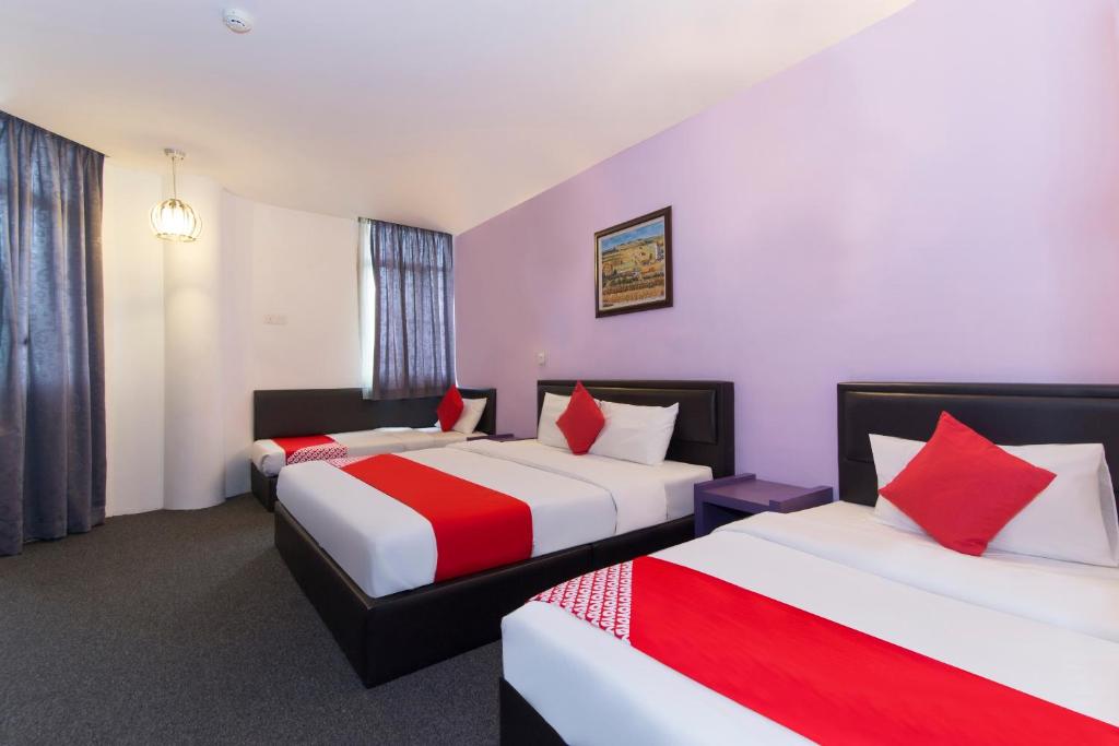 a hotel room with two beds with red and white sheets at Super OYO 442 Marvelton Hotel in Butterworth
