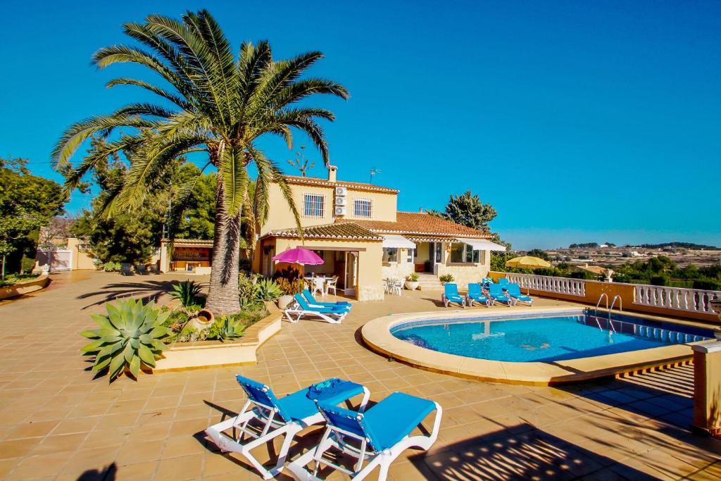 a pool with chairs and a palm tree and a house at Finca Palacios - comfortable holiday accommodation in Benissa in Benissa