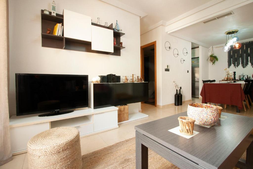 sala de estar con TV grande y mesa en El apartamento de Maria Jose en Torrevieja
