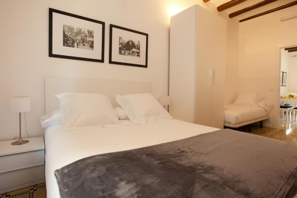 um quarto com uma grande cama branca e uma cadeira em Barnapartments Basic Gracia em Barcelona