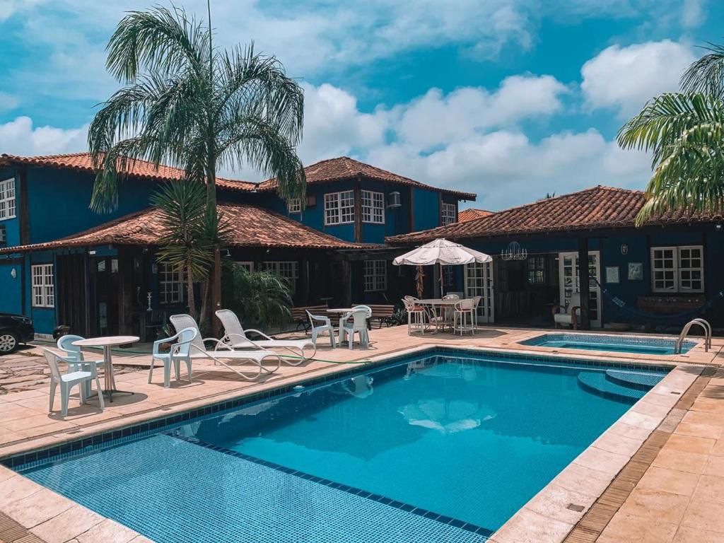 uma piscina em frente a uma casa com palmeiras e cadeiras em Recanto Al Mare em Búzios