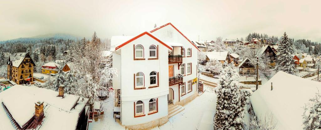 een stad bedekt met sneeuw met huizen en bomen bij Pensiunea Nicolas in Sinaia