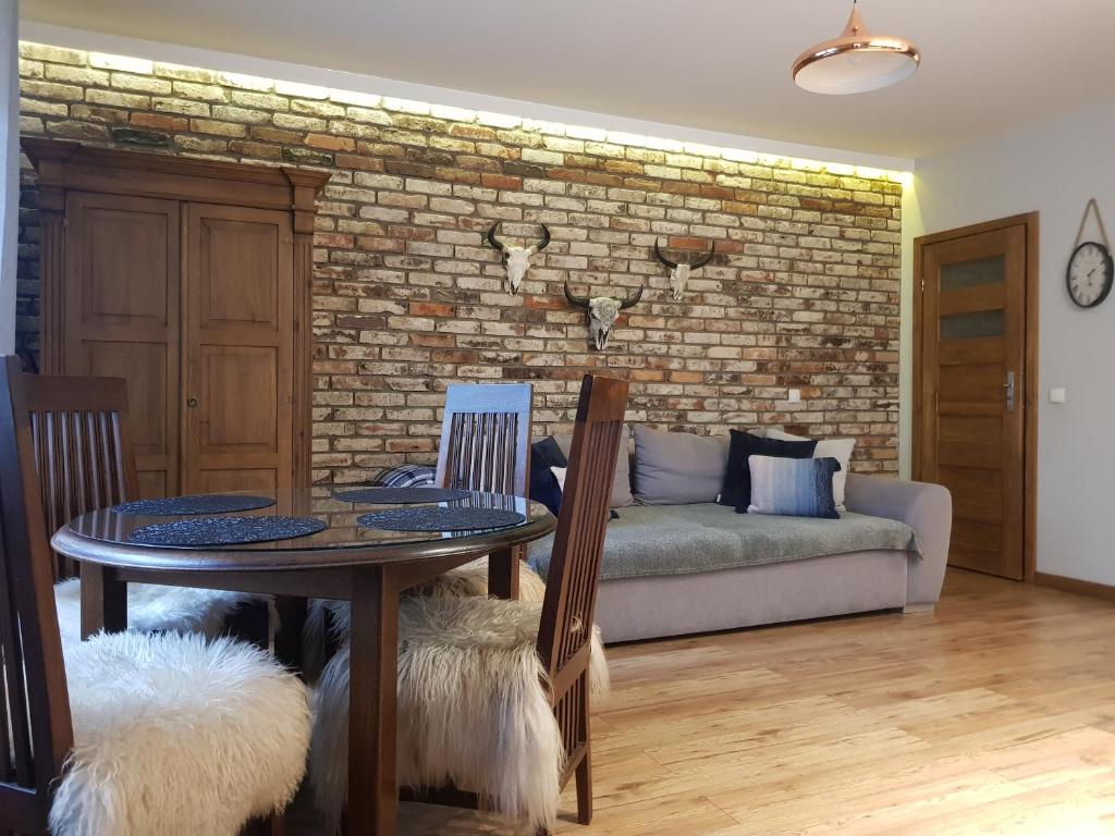 a living room with a table and a brick wall at Apartamenty 33 in Zakopane