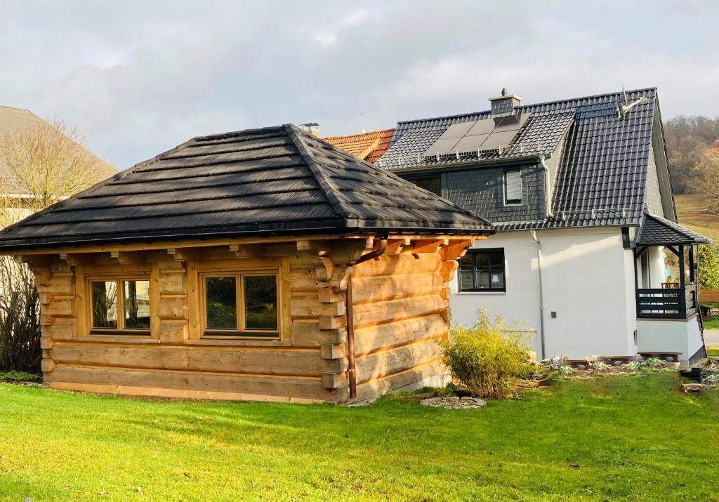 una cabaña de madera frente a una casa en Balance Apartments by M&A - Ferienhaus Dohrenbach en Witzenhausen