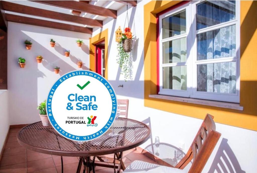 a patio with a table and chairs and a sign that reads clean and safe at Casinha D'Avó Guesthouse in Lagos