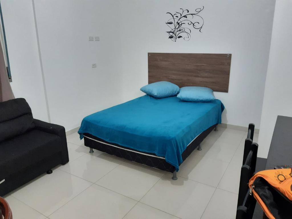 a bedroom with a bed with blue pillows and a chair at Kitnet Guarujá Pitangueiras (sem garagem) in Guarujá