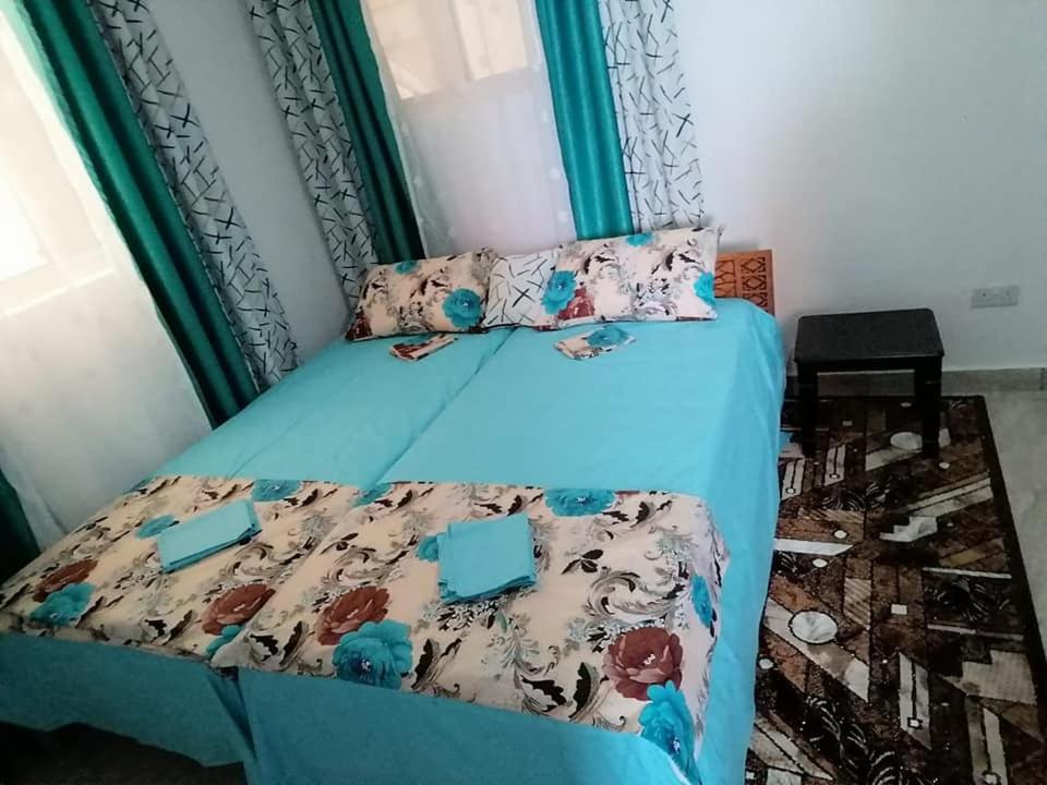 łóżko z niebieską kołdrą i poduszkami w obiekcie Mtwapa Pride Apartment 4th Floor w mieście Mtwapa