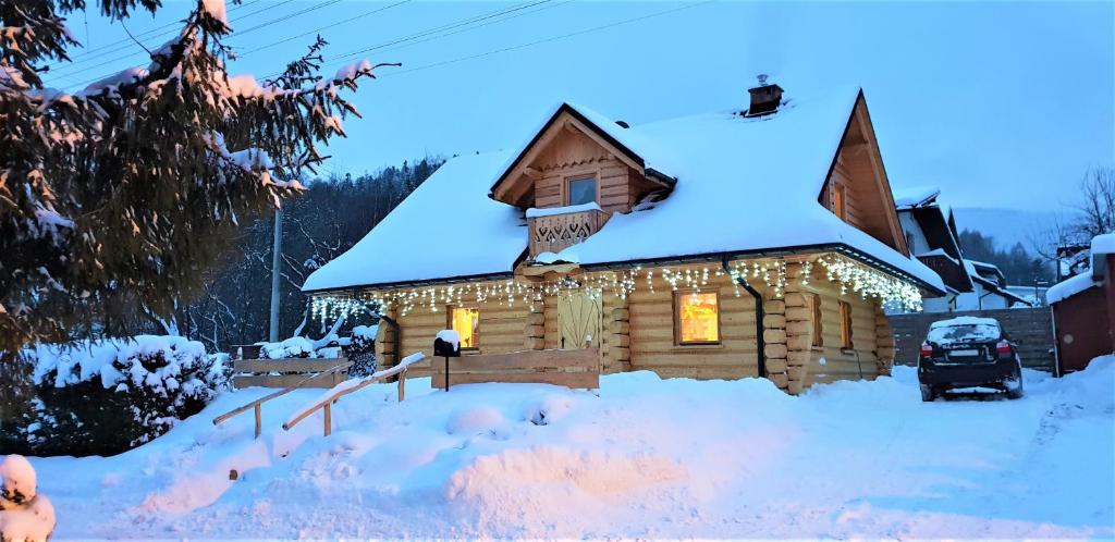 una cabaña de madera cubierta de nieve con luces. en Świerkowy Raj en Ustroń