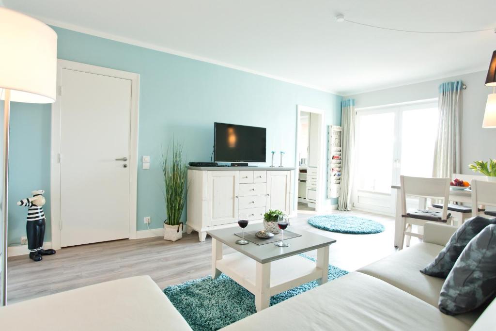 sala de estar con sofá blanco y TV en Ferienwohnung Meeresrausch, en Westerland