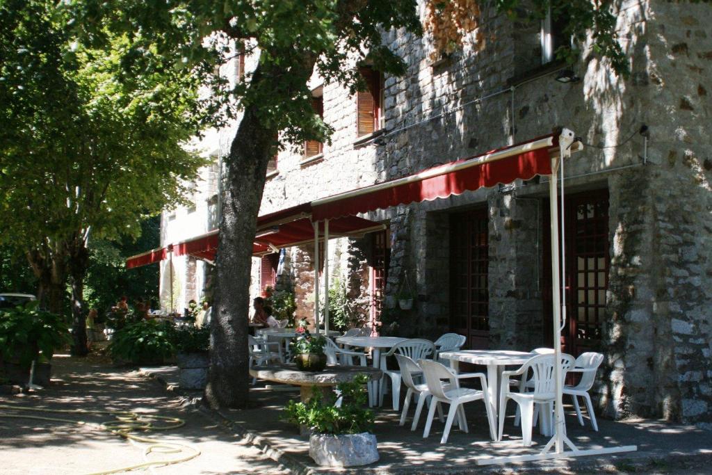 une table et des chaises assises à l'extérieur d'un bâtiment dans l'établissement Hôtel - Pub Le Petit Bosquet, à Santo-Pietro-di-Venaco