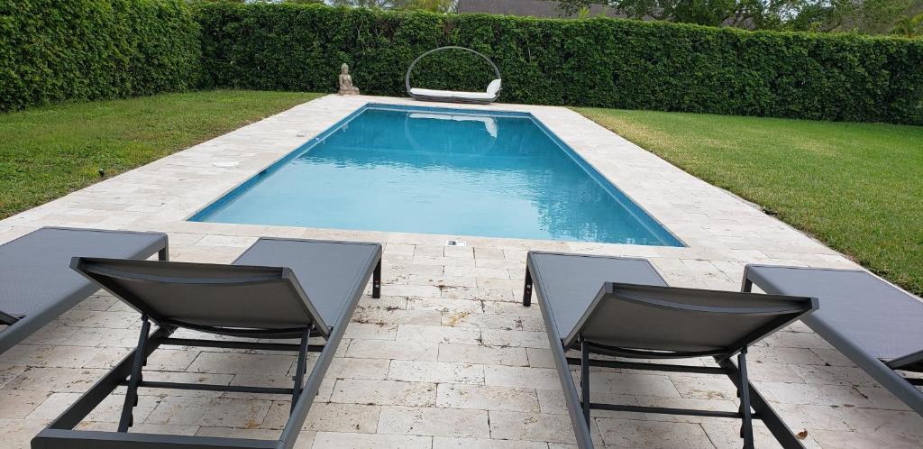 a swimming pool with two chairs and a table at Casa Catalina in Homestead