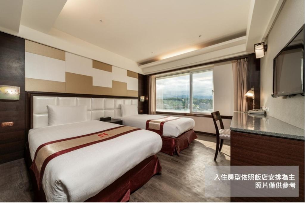 a hotel room with two beds and a television at Fish Hotel Taitung in Taitung City