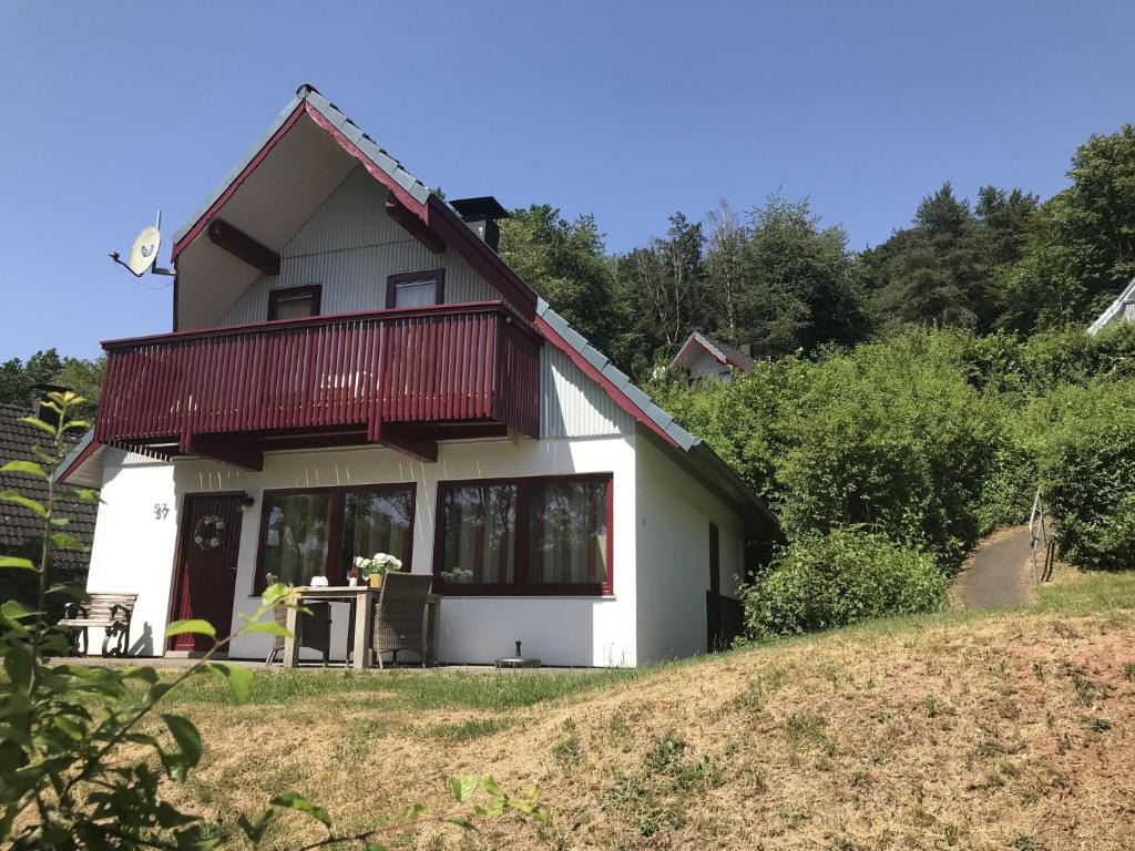 a white house with a red roof on a hill at Holiday home in Reimboldshausen with balcony in Kemmerode