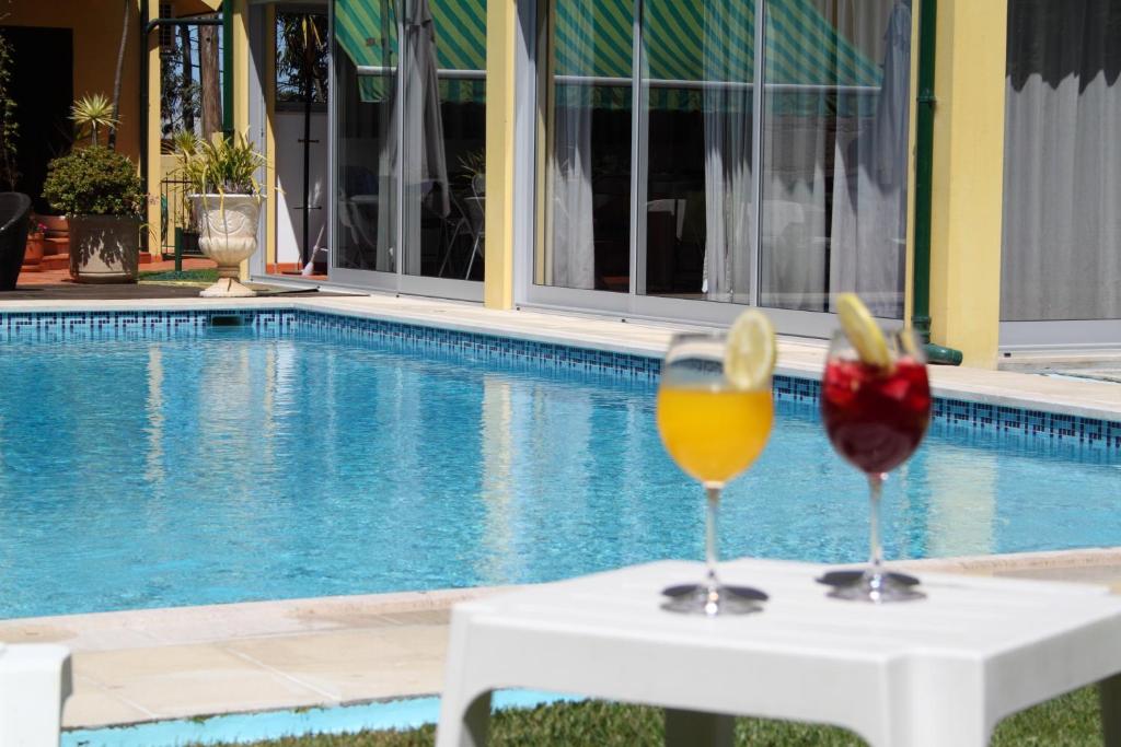 - deux verres de vin assis sur une table à côté d'une piscine dans l'établissement Guesthouse Pool & Sea Espinho Oporto, à Espinho