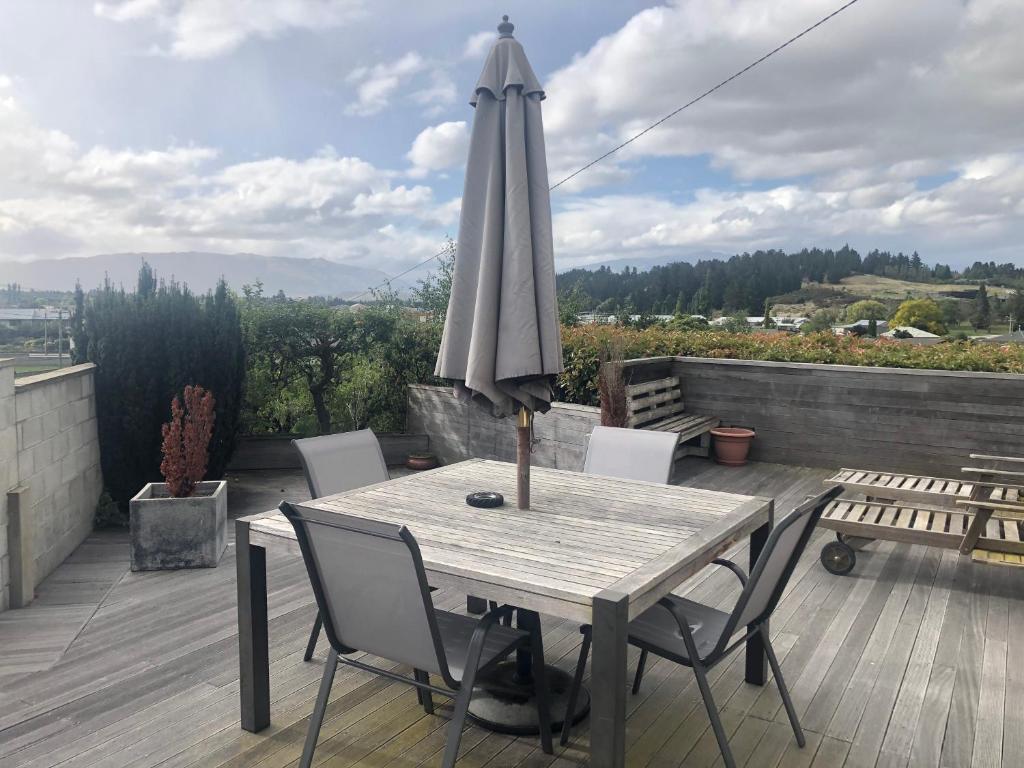 a wooden table with an umbrella on a deck at Solway House in Alexandra