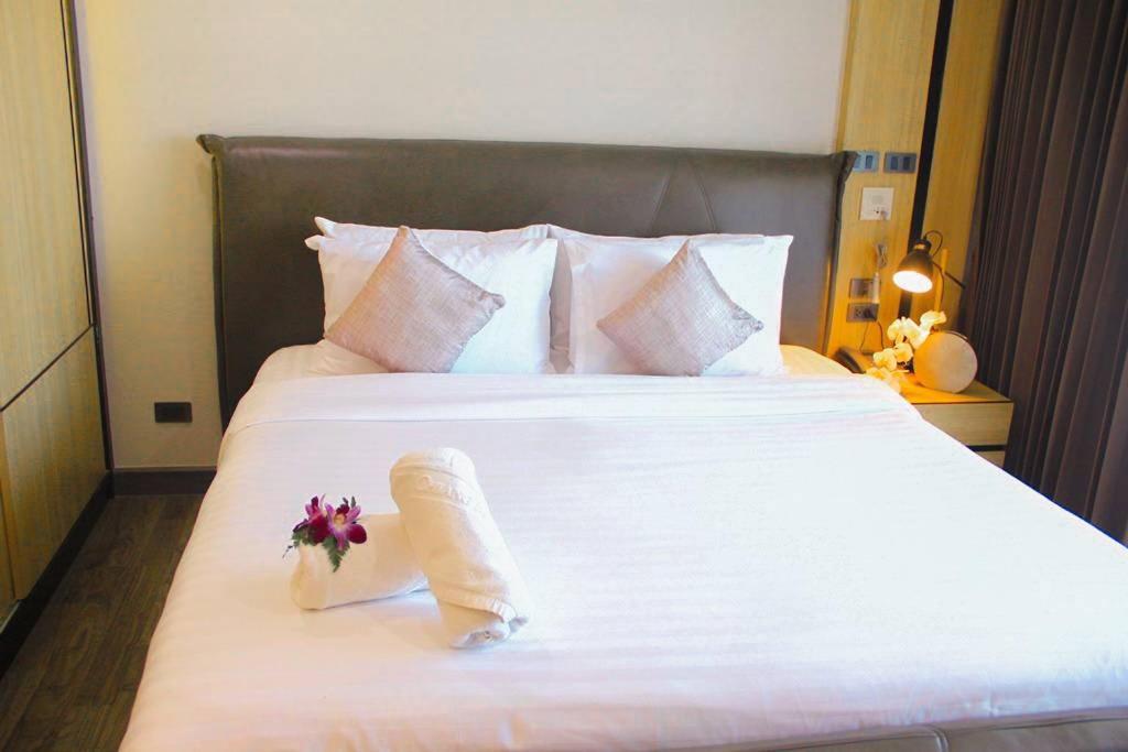 Una gran cama blanca con un ramo de flores. en Wellness Chiang Mai Hotel en Chiang Mai