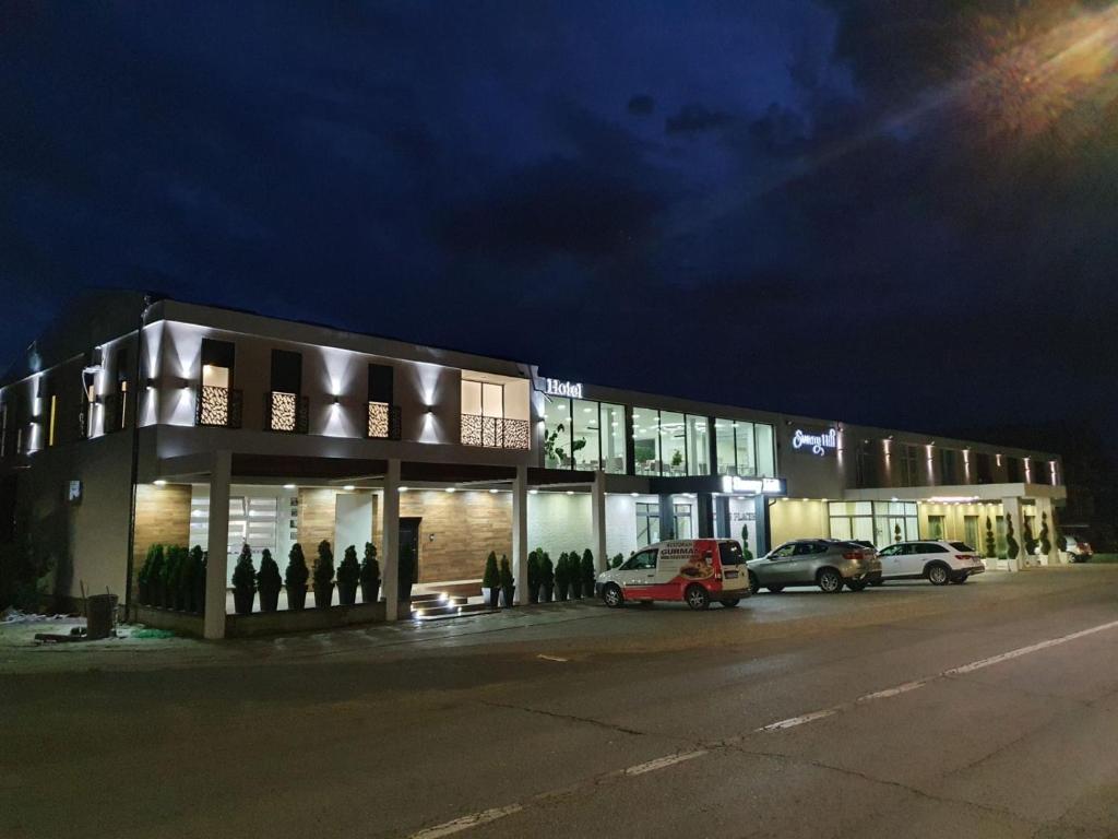 a group of people standing outside of a building at night at Sunny Hill Garden in Stara Pazova