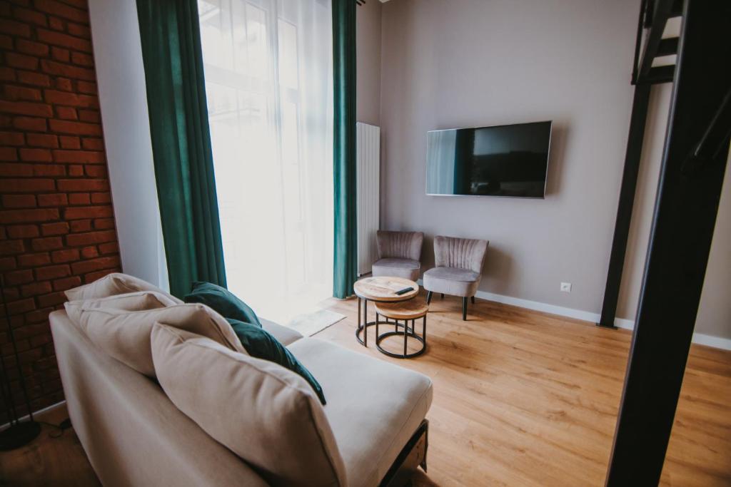 - un salon avec un canapé et une télévision dans l'établissement Apartament Green - Piotrkowska 37, à Łódź