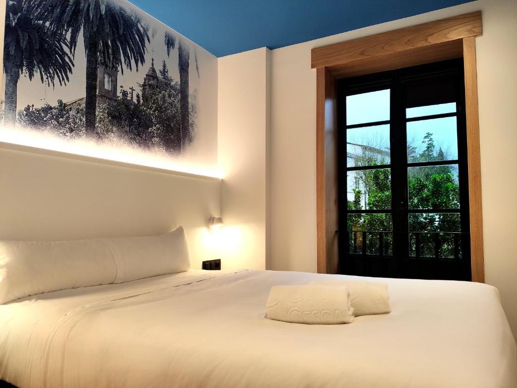 1 dormitorio con cama blanca y ventana en Alameda Rooms Santiago, en Santiago de Compostela