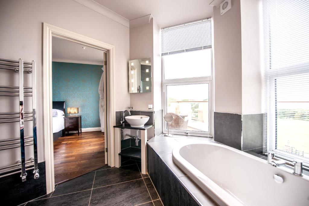 a bathroom with a bath tub and a bedroom at The Woolacombe Bay Hotel in Woolacombe