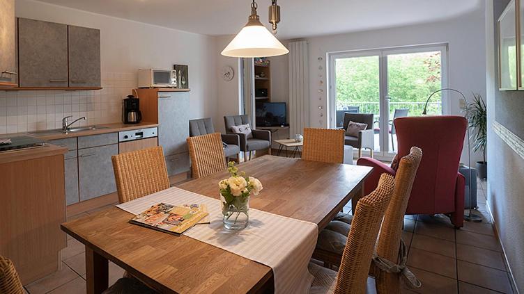 a kitchen and living room with a wooden table with flowers on it at Gästehaus Simonis in Pünderich