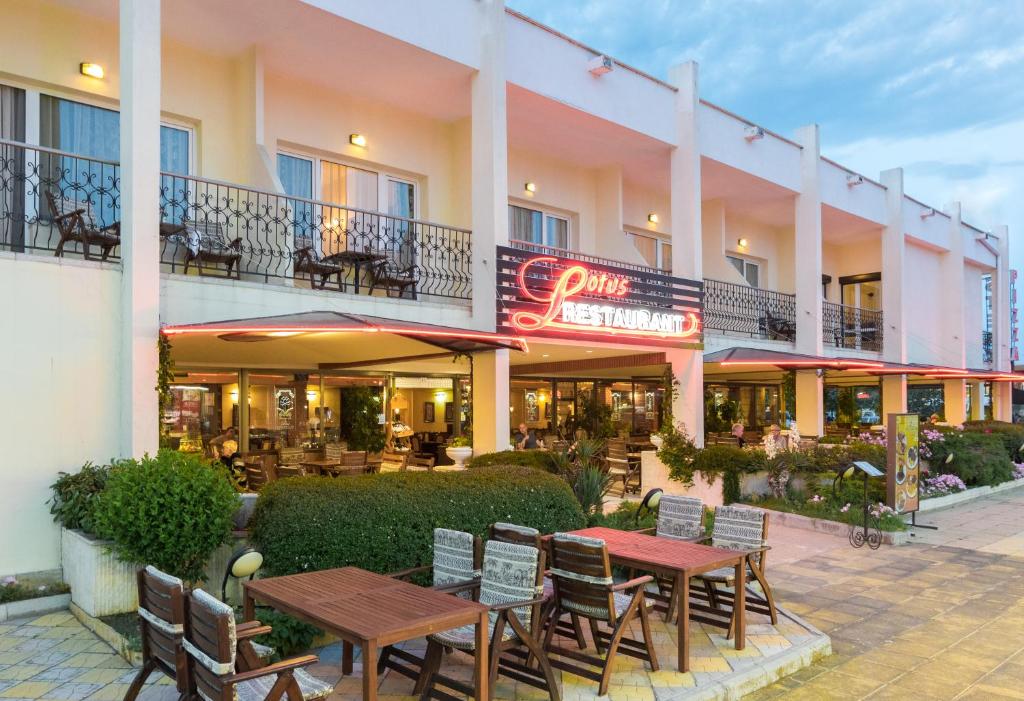 un hotel con mesas y sillas fuera de él en Lotus Family Hotel - Free Parking en Sunny Beach