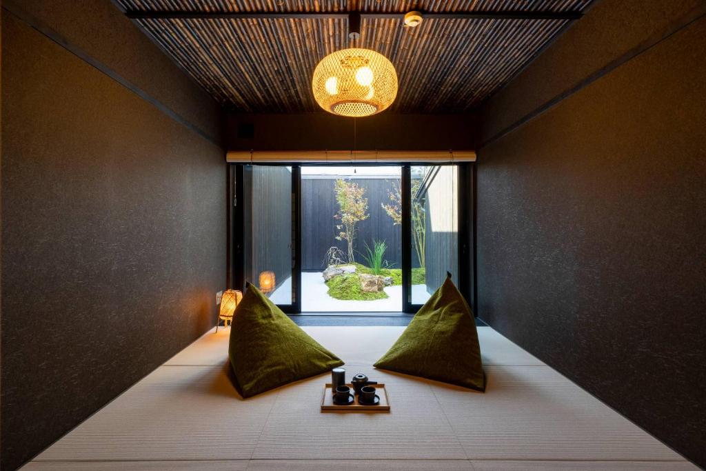 a room with a bed with green pillows and a window at Yoinotake Machiya House in Kyoto