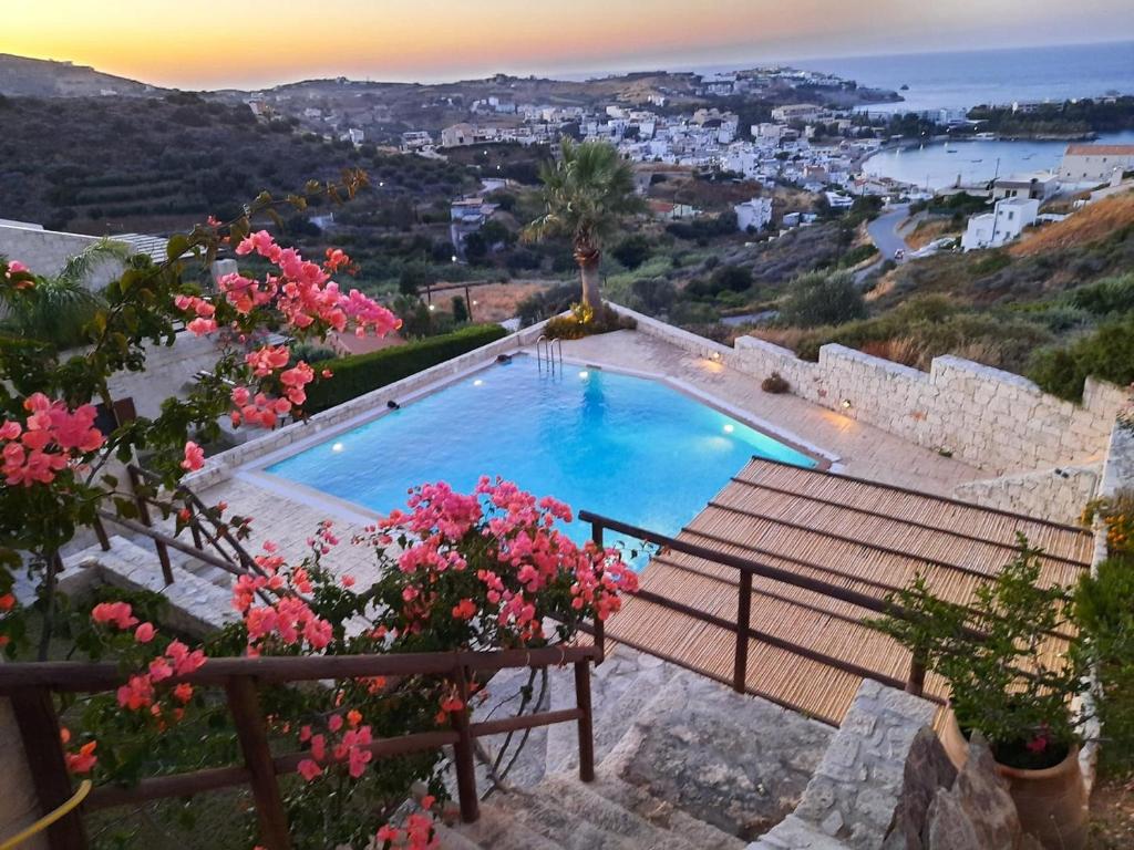 una piscina con un banco y flores rosas en Rafaello Luxury Villa en Agia Pelagia