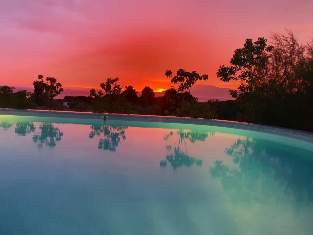 uma piscina com um pôr-do-sol ao fundo em Villa individuelle avec piscine privée chauffée proche commerces et plage em Porticcio