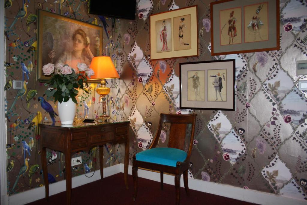 Cette chambre comprend une table, une chaise et des photos sur le mur. dans l'établissement Hôtel De Nice, à Paris