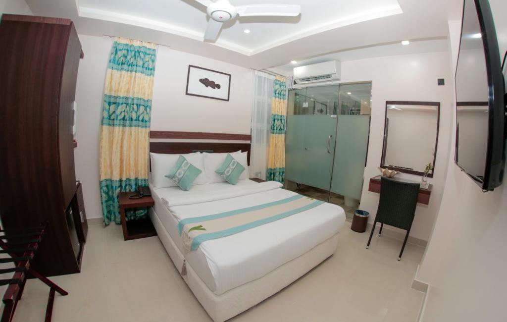 a bedroom with a large white bed and a mirror at The White Harp Beach Hotel in Hulhumale