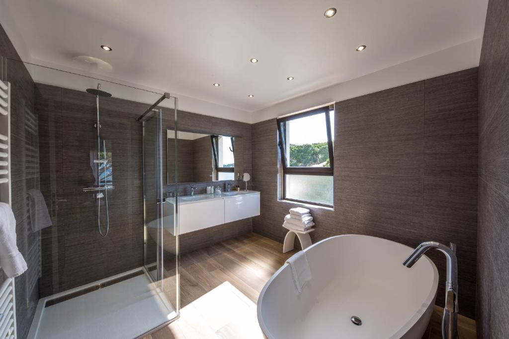 a bathroom with a tub and a shower and a sink at Hôtel La Roya in Saint-Florent