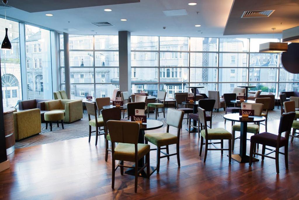 a restaurant with tables and chairs and large windows at Leonardo Hotel Aberdeen in Aberdeen