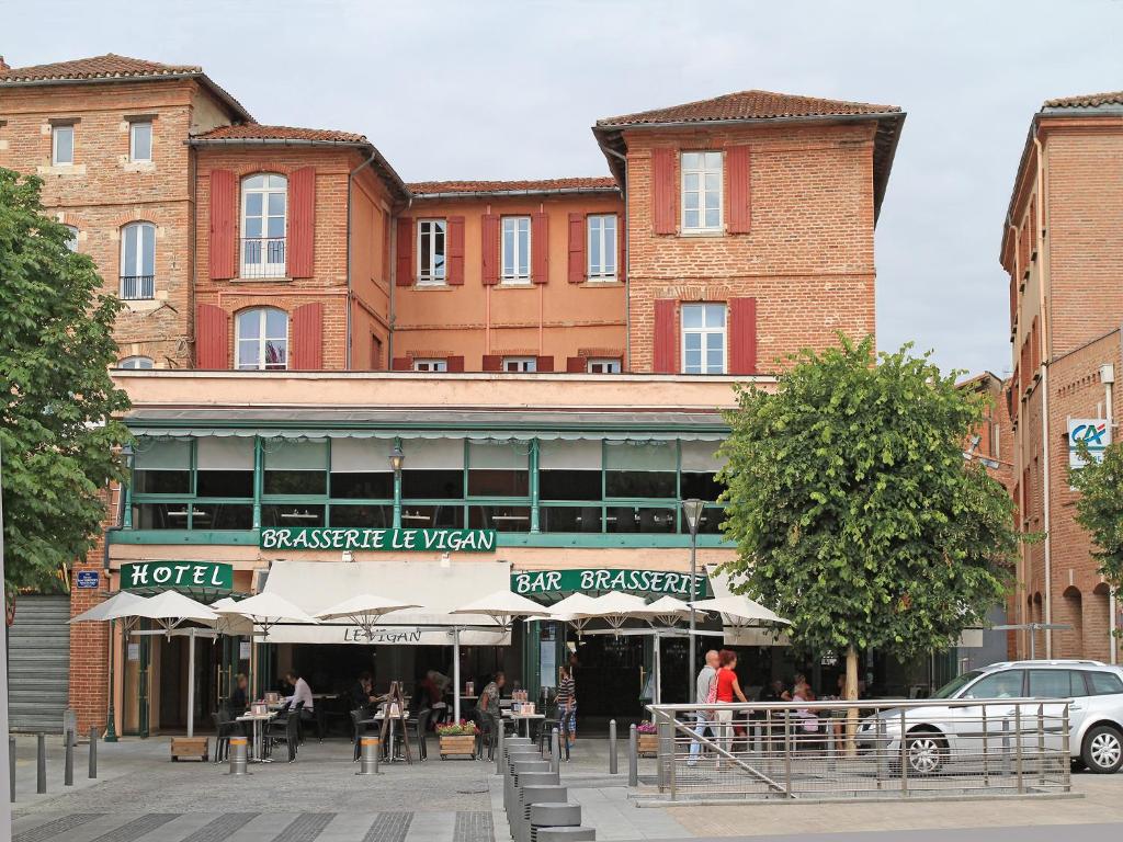 a large brick building with people sitting outside of it at Hôtel du Vigan in Albi